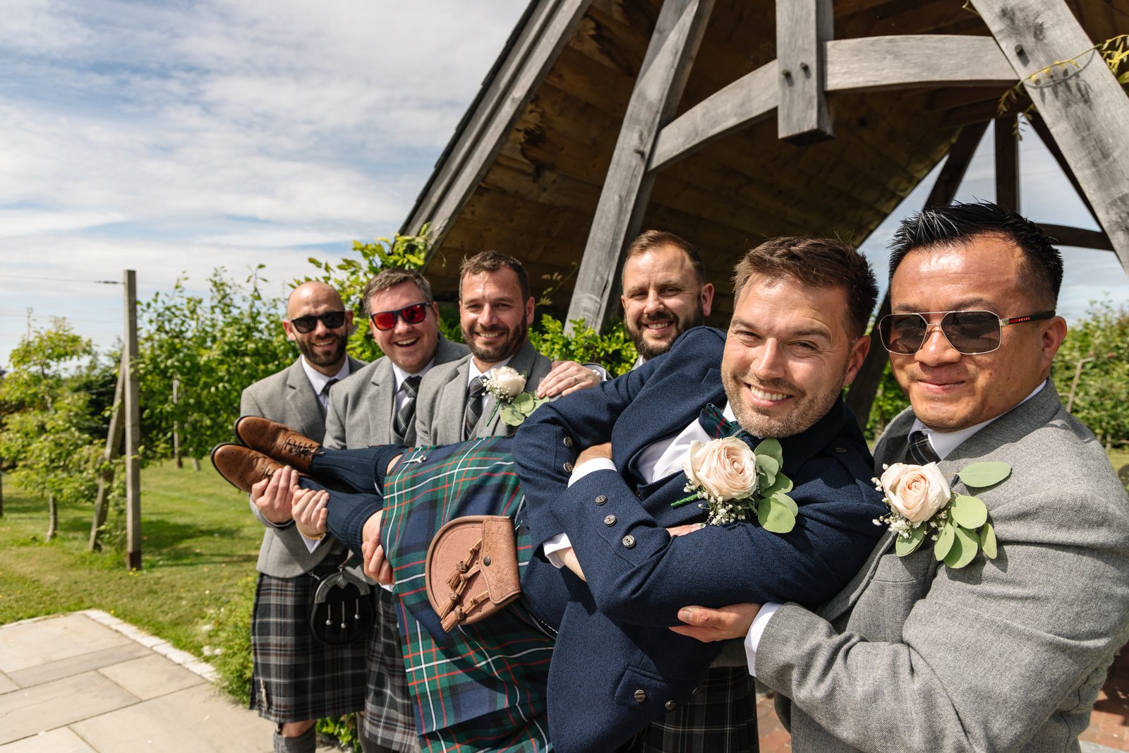 The groomsmen lifting the groom off his feet outside