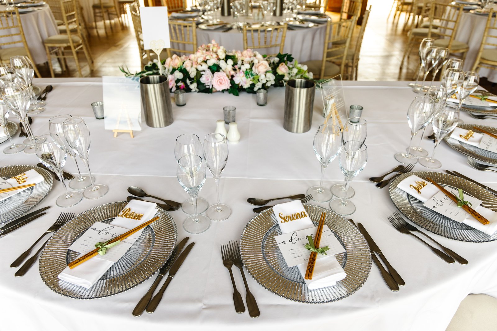 The top table laid with flowers and gold chargers for the wedding breakfast