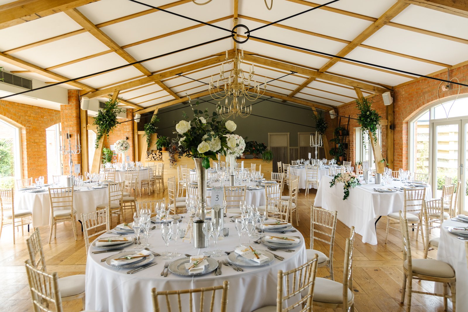 Round tables set for dinner under the pitched roof at Cider Mill Barns