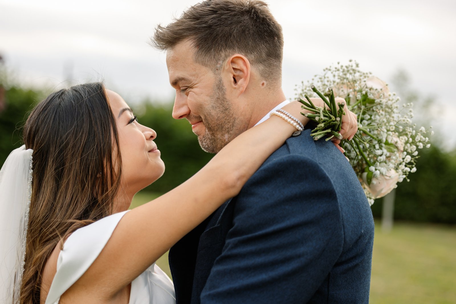 The bride with her arms around the groom's neck, holding her bouquet