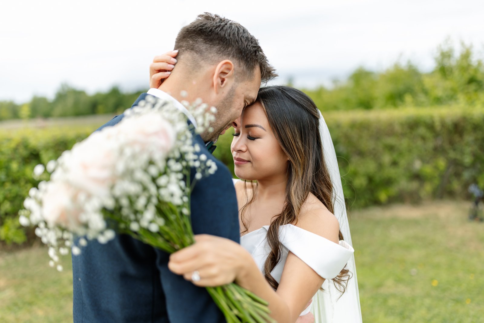 The couple close together with the bouquet held out in front of them