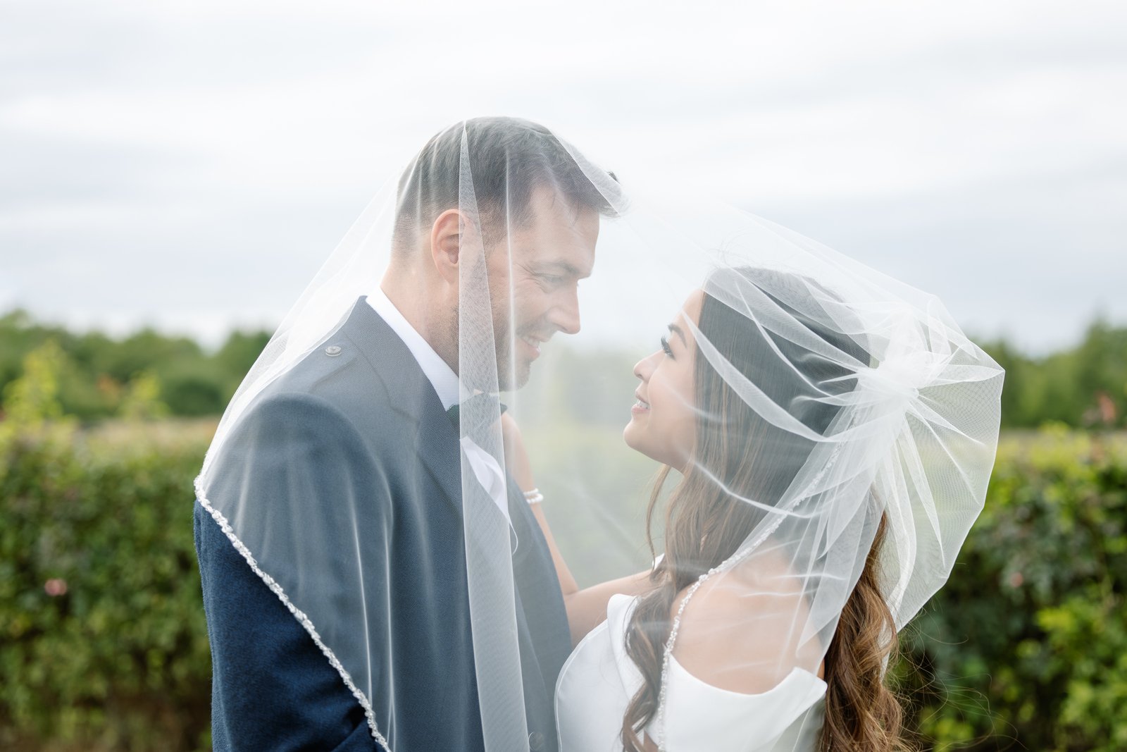 The couple under the veil, face to face, with the rows behind them