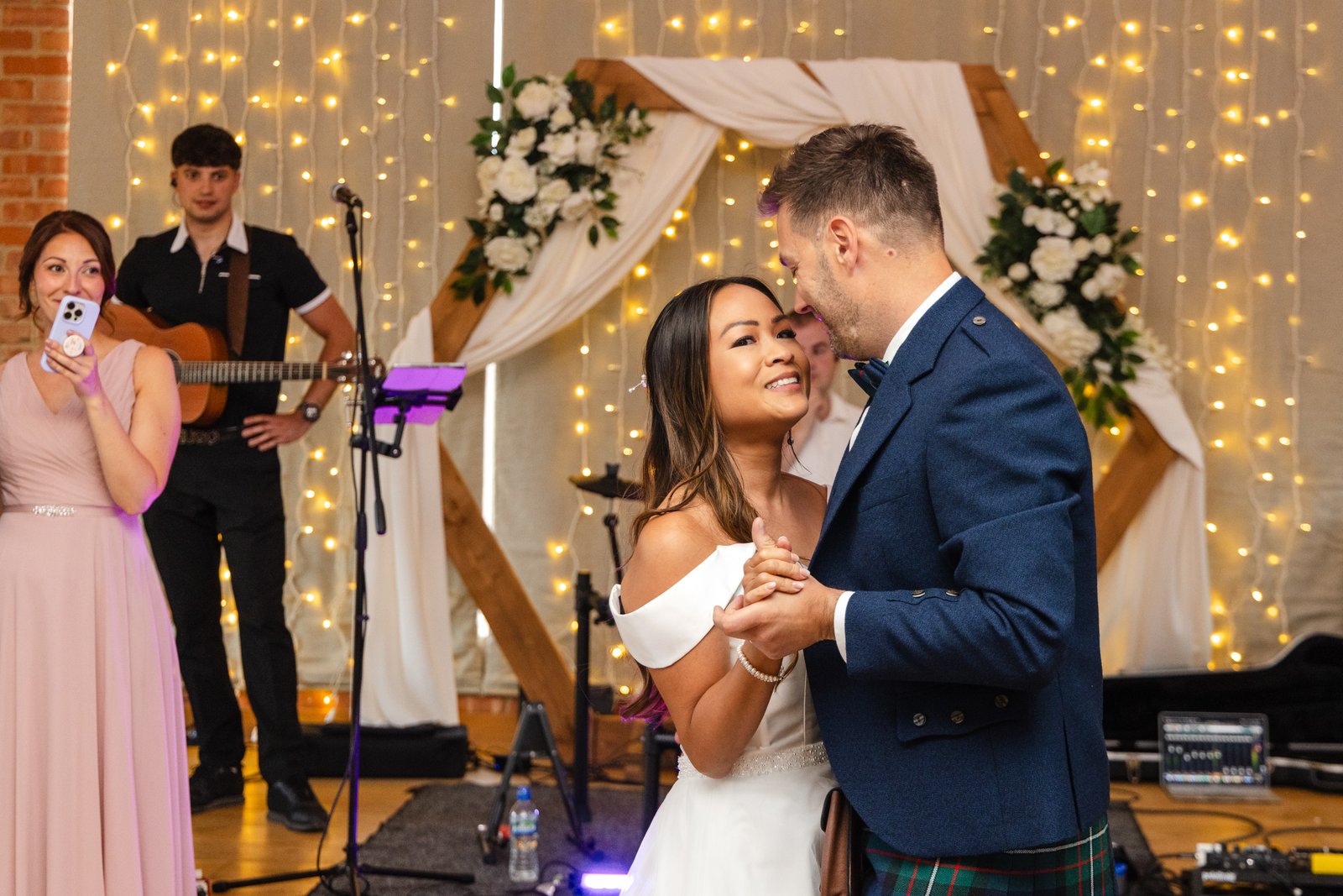The couple's first dance in front of the band and a curtain of fairy lights