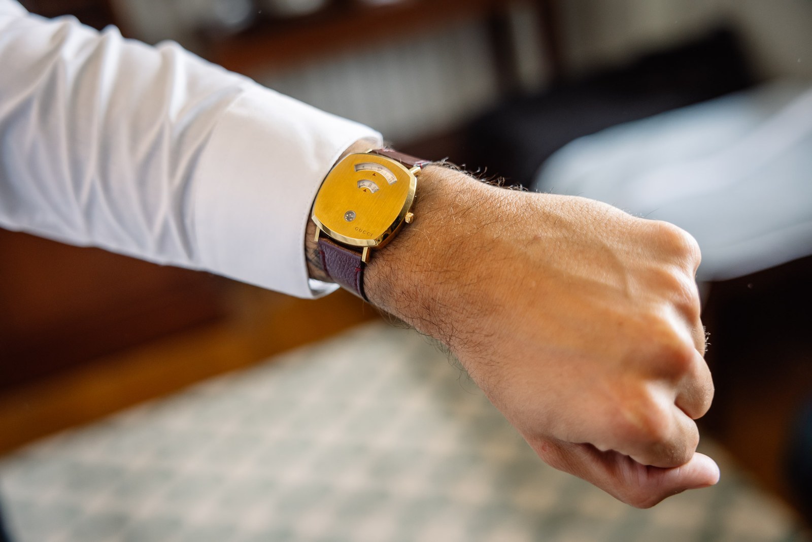 Close-up of a wrist and yellow-faced watch on a burgundy strap
