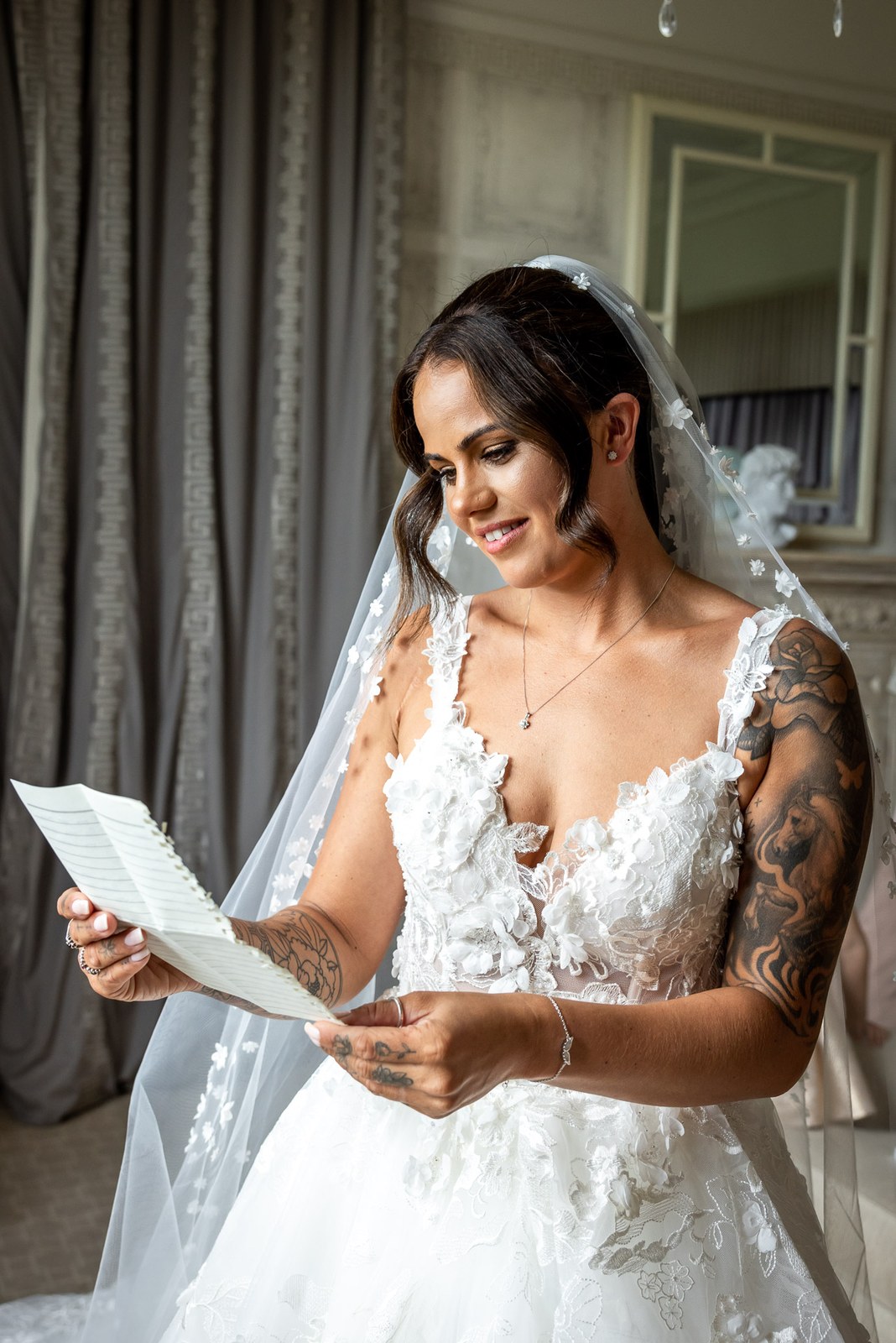 The bride reads a handwritten note, her veil draped over her shoulder