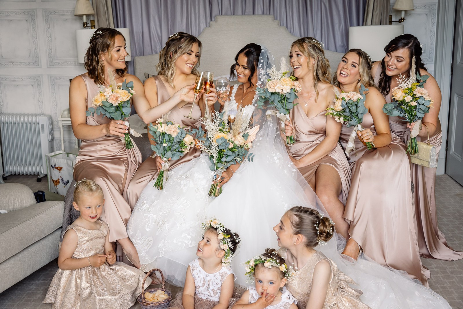 The bride surrounded by her bridesmaids and flower girls holding their bouquets