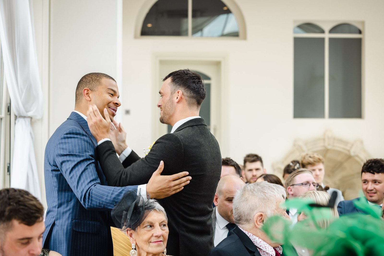 Two men share an emotional embrace as guests take their seats