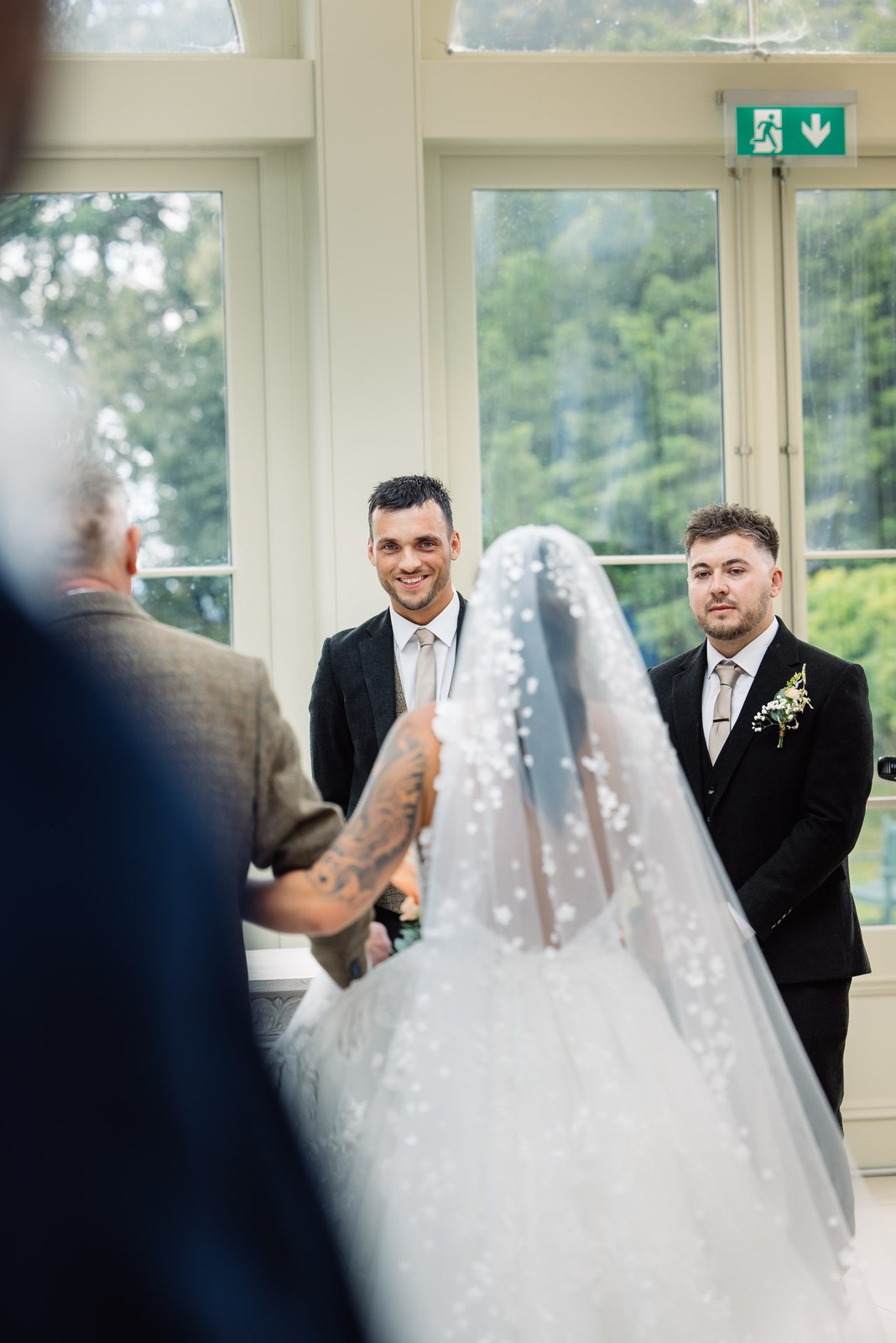 The bride joins the groom at the front of the light-filled orangery