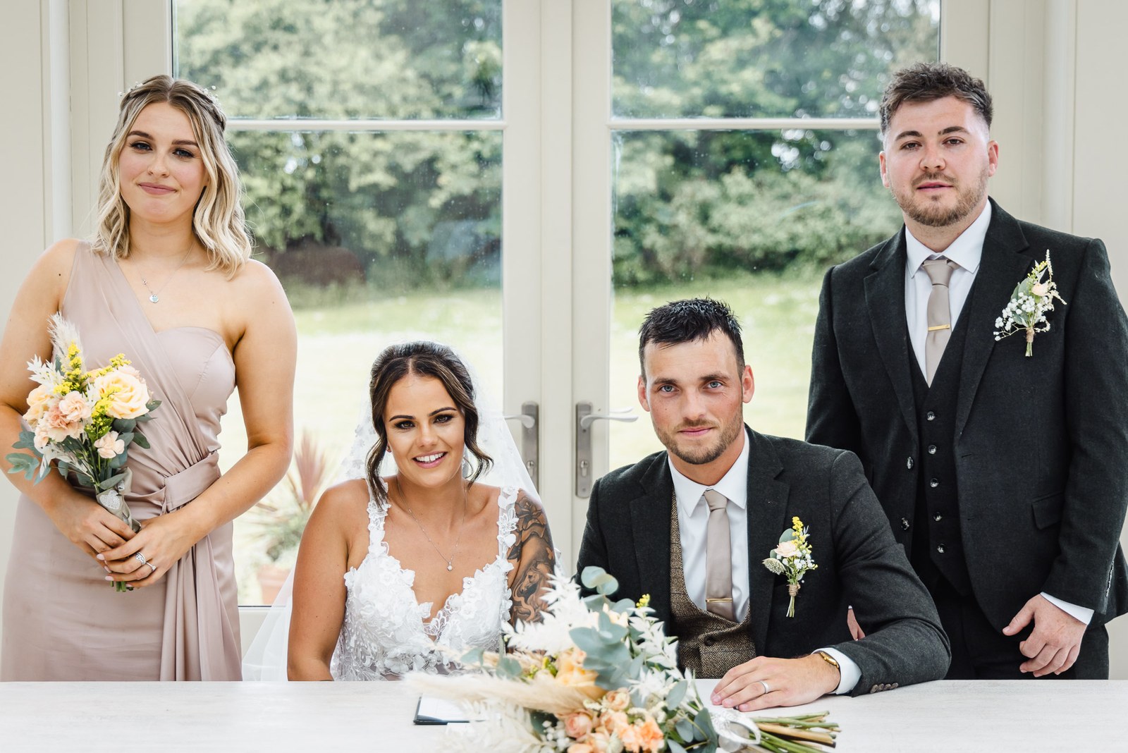 The couple sign the register with witnesses in the orangery at Clevedon Hall