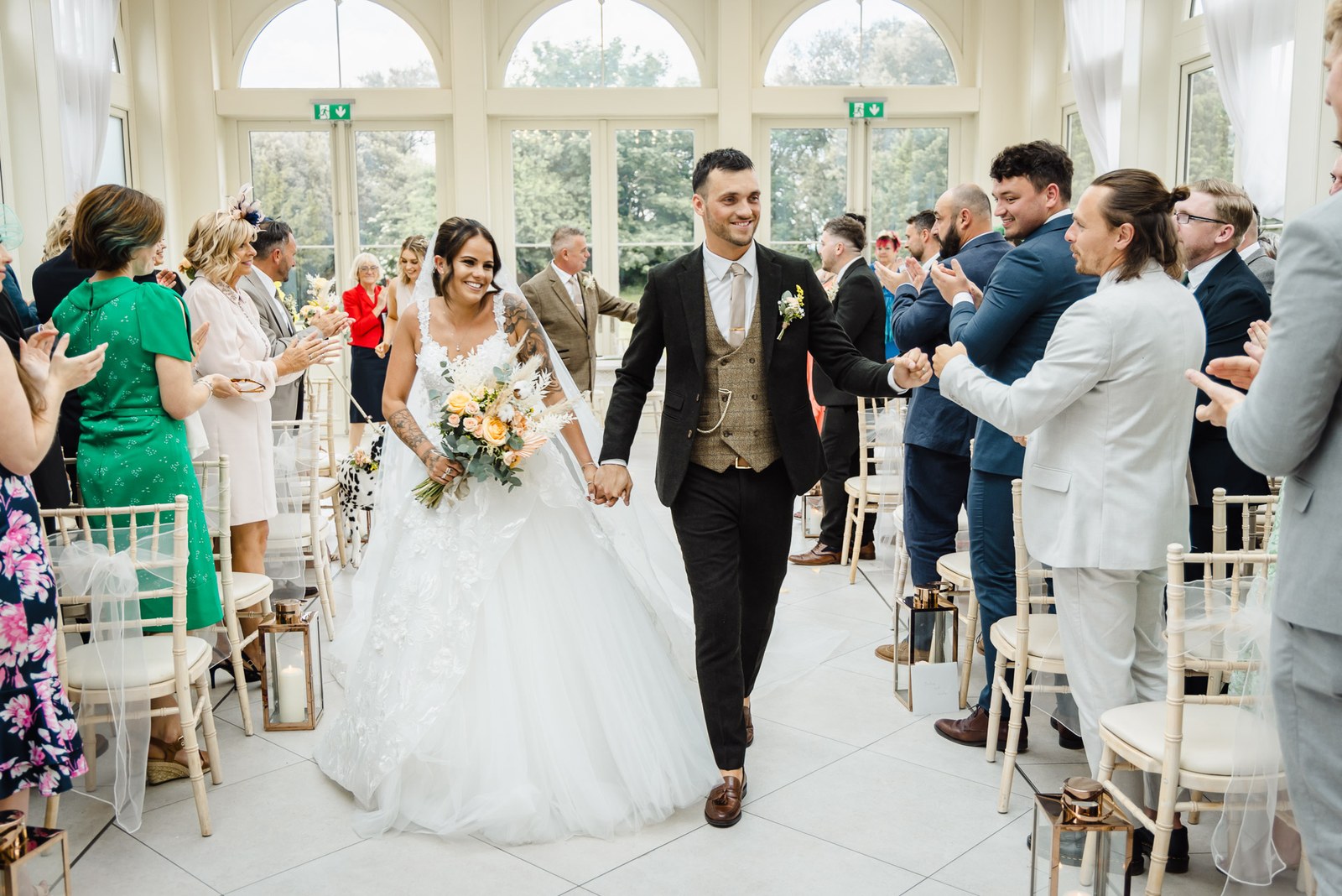 The newlyweds process down the aisle between applauding guests