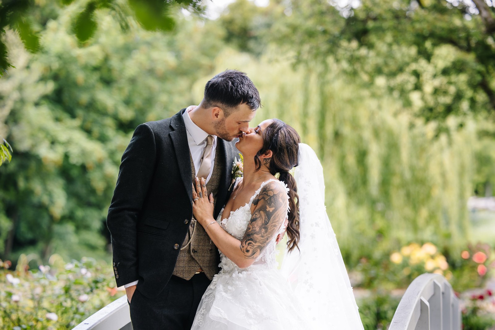 The couple kiss among the greenery of the gardens