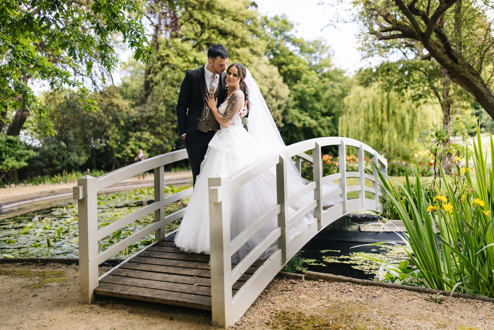 The couple pause on a white ornamental bridge over the lily pond at Clevedon Hall