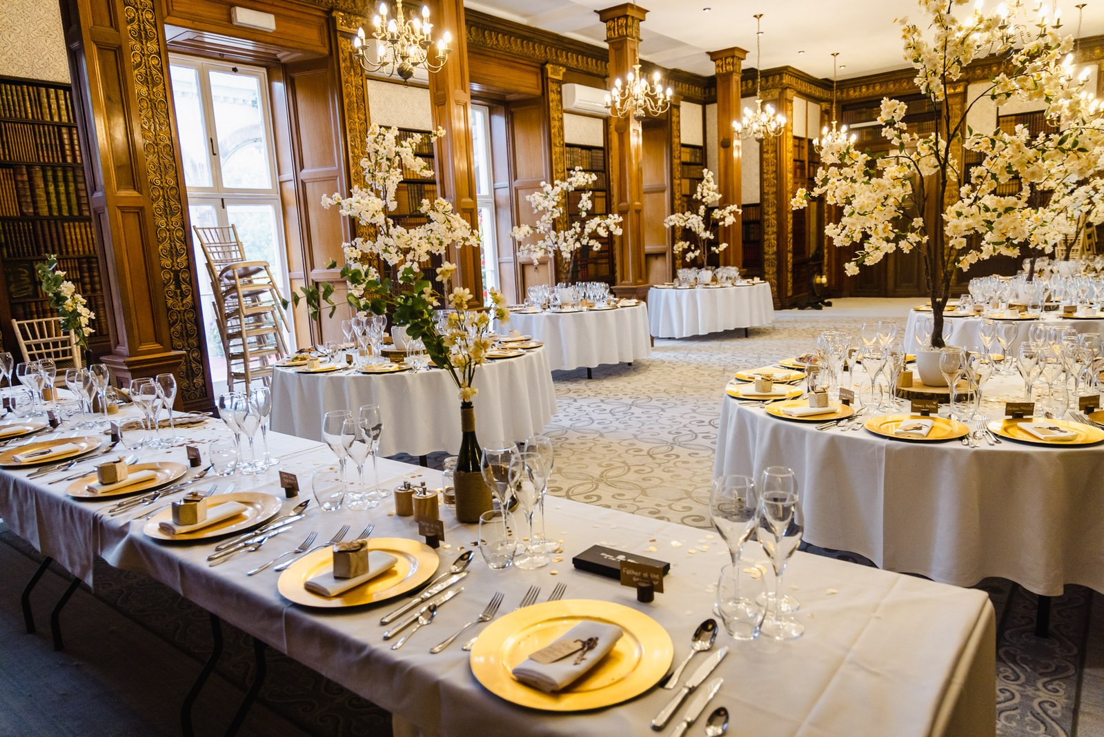 The wood-panelled library at Clevedon Hall set with tables and blossom trees