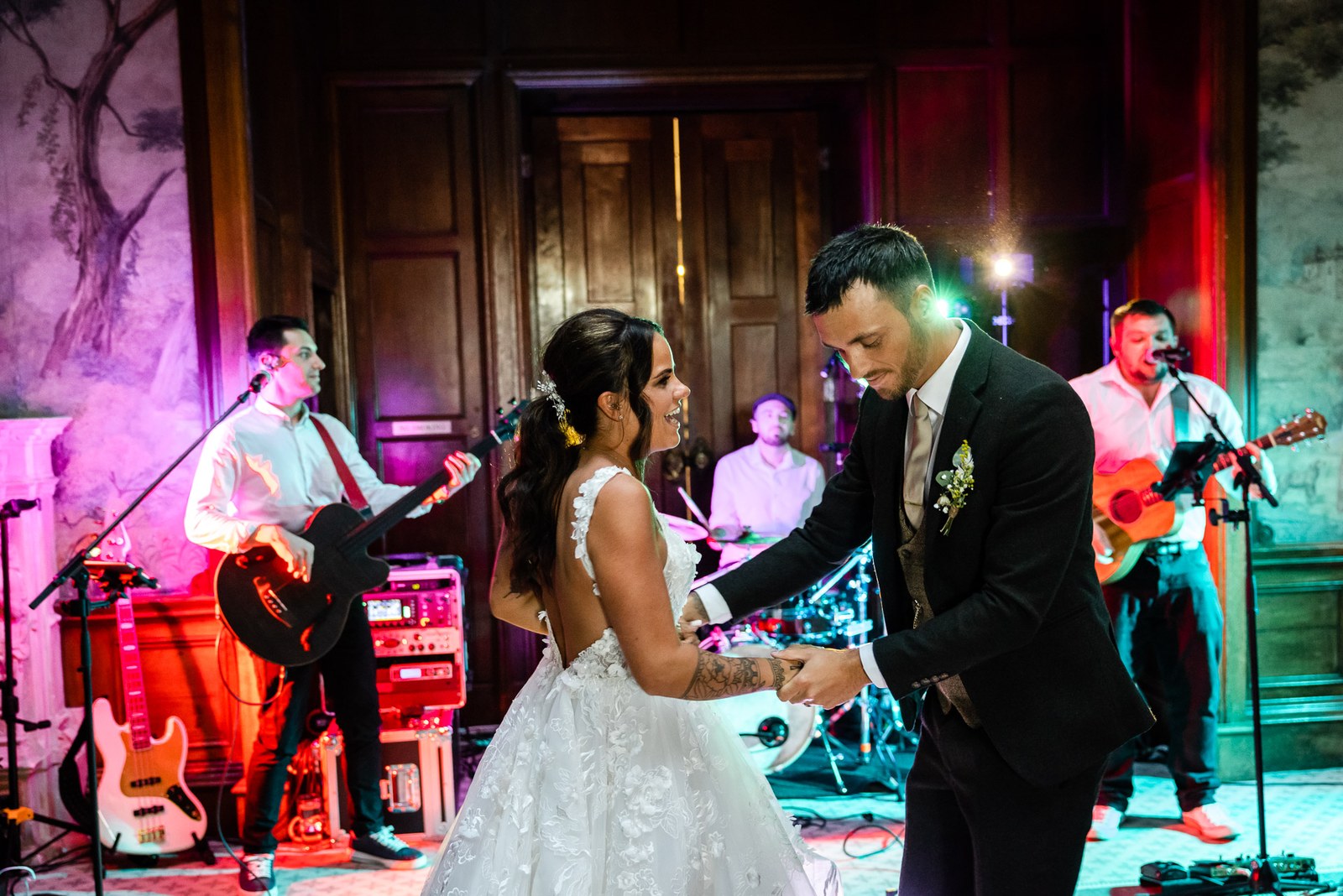 Bride and groom dance in front of the live band under coloured lights