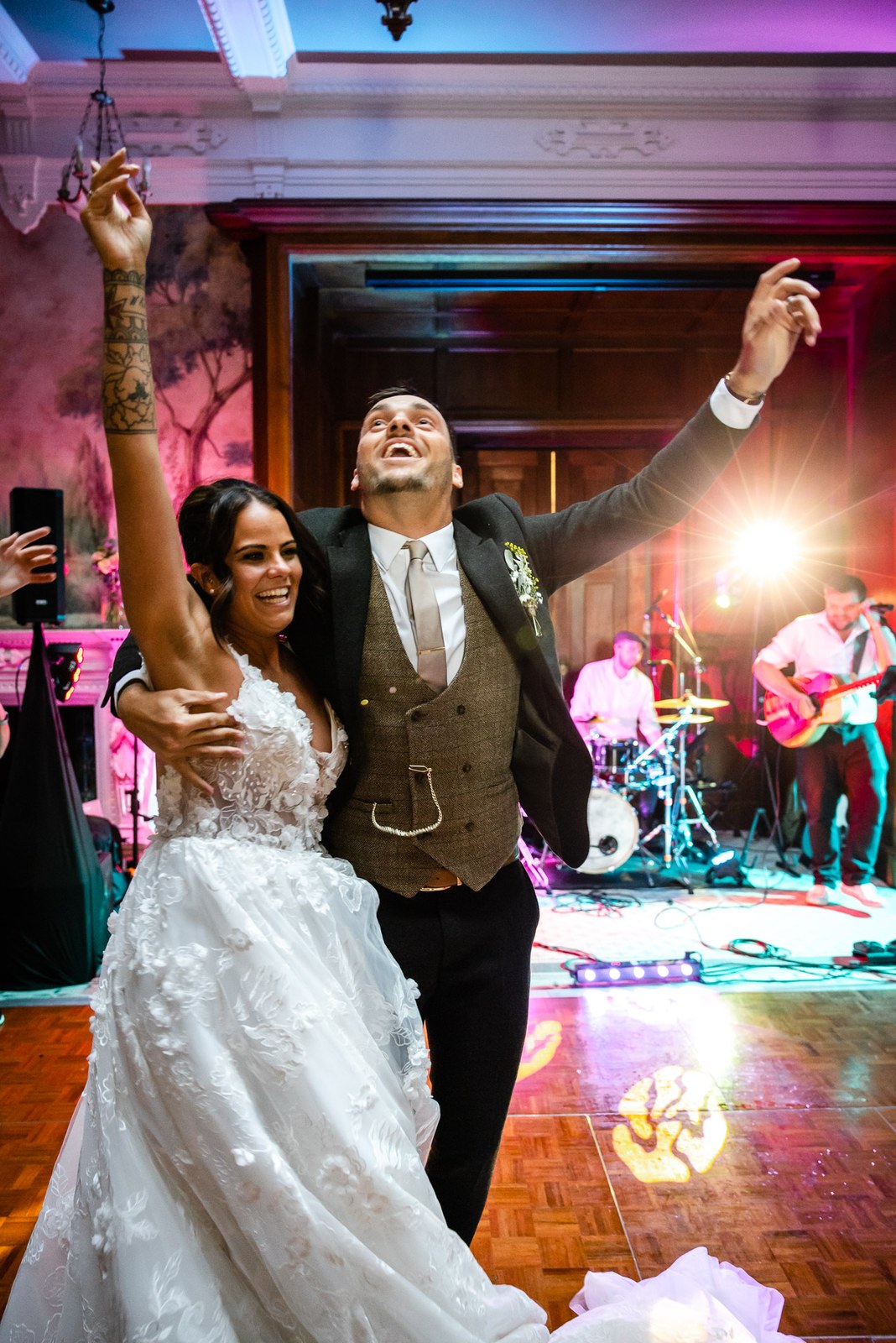 The newlyweds celebrate with arms raised on the dancefloor as the band plays