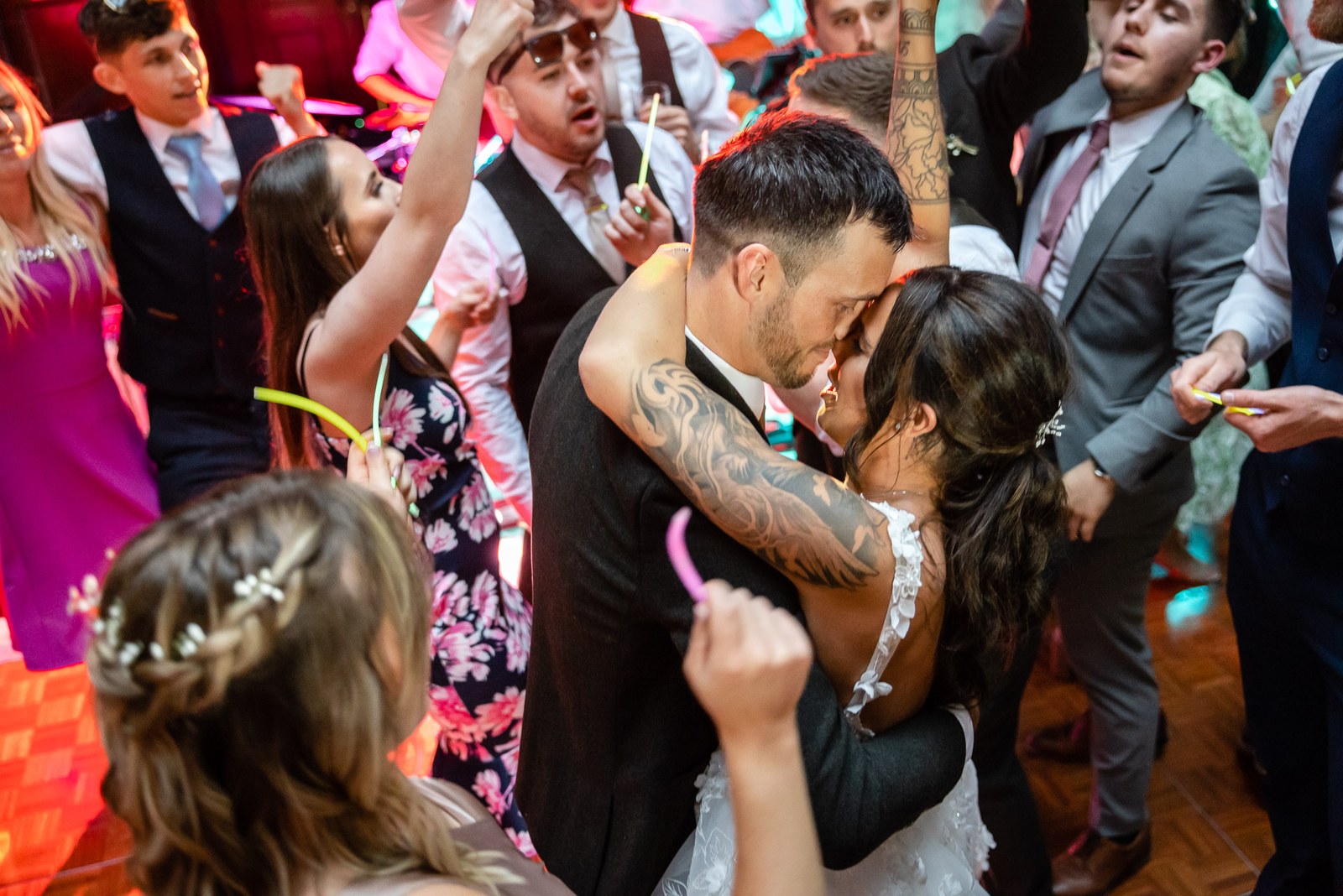 The couple dance closely amid guests on a crowded dancefloor