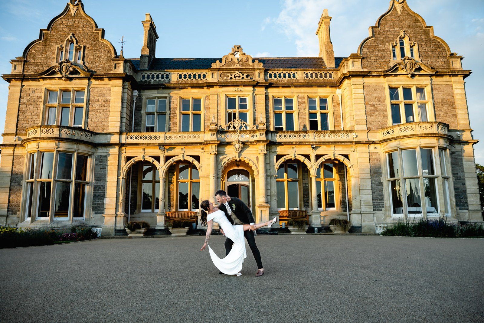 The couple dip and dance before the floodlit facade of Clevedon Hall at dusk