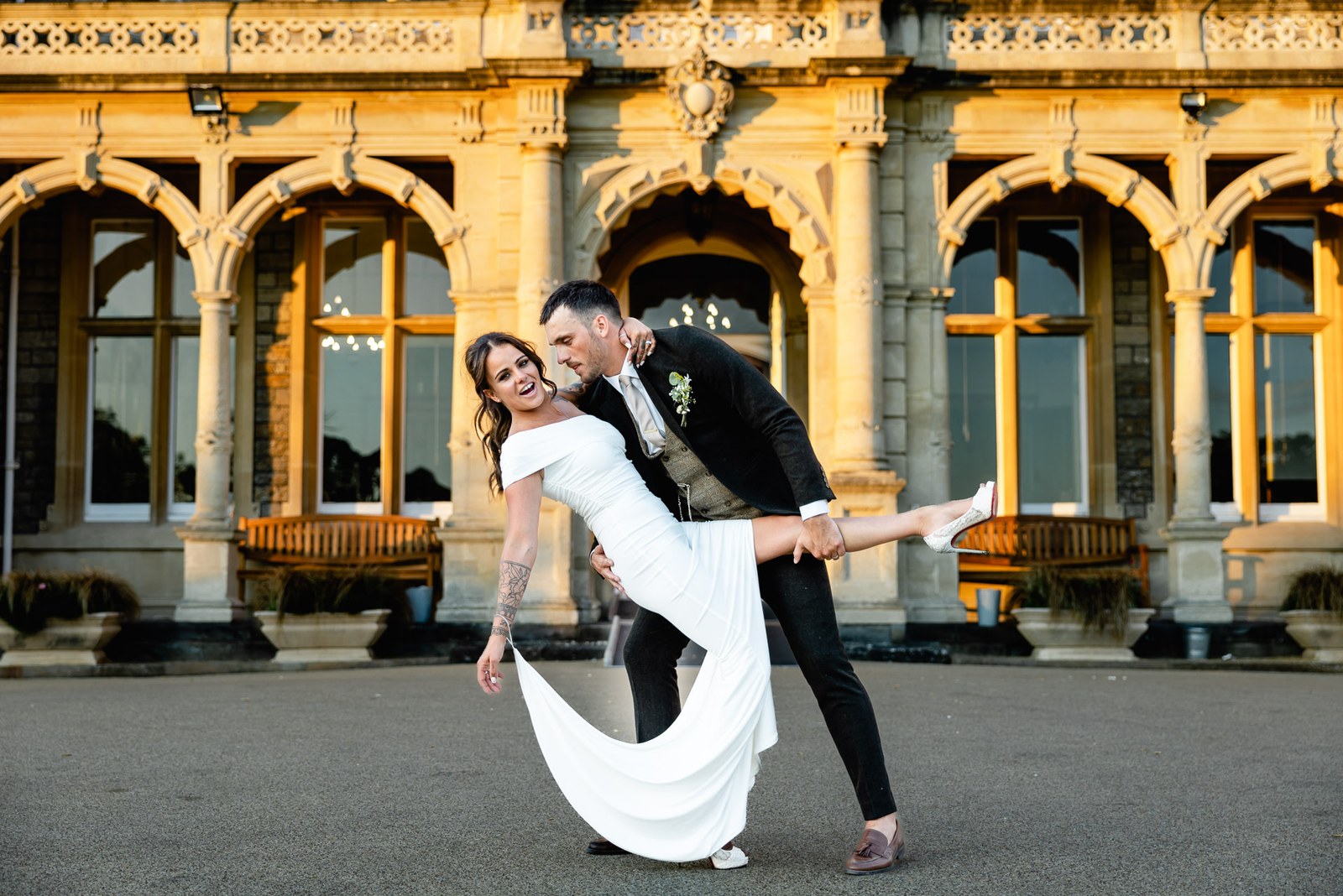 Bride and groom strike a dance pose before the lit arched windows of the venue