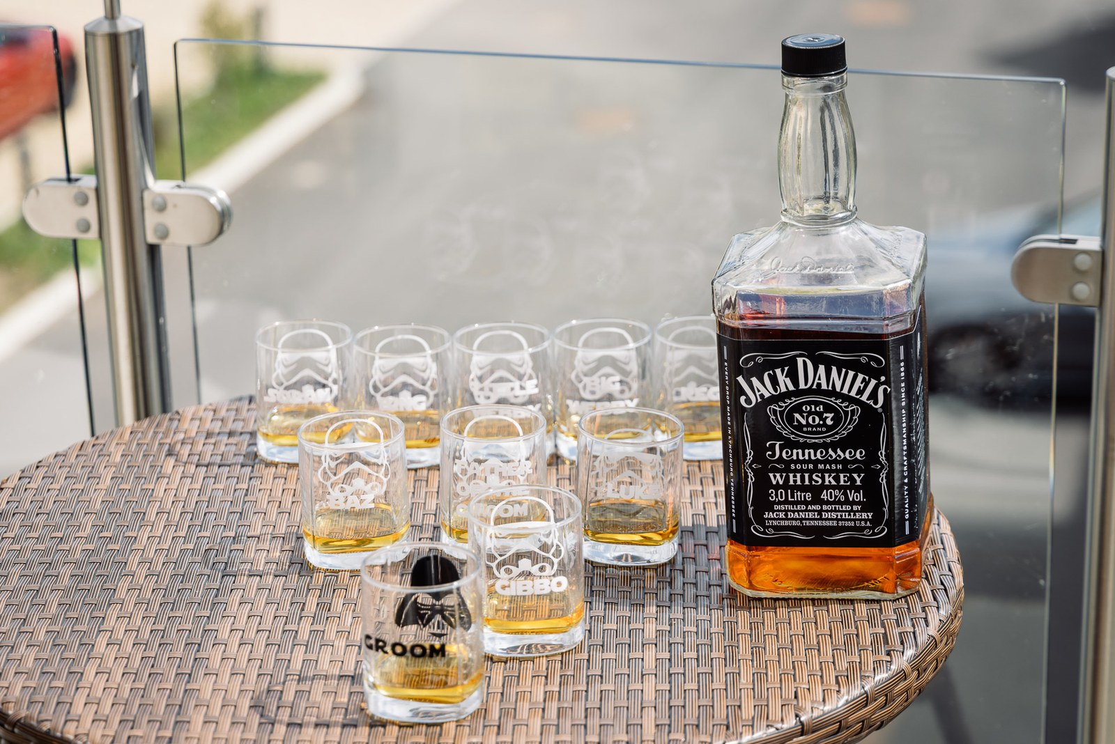 A whiskey bottle and novelty Star Wars shot glasses set out on a table for the groom's party