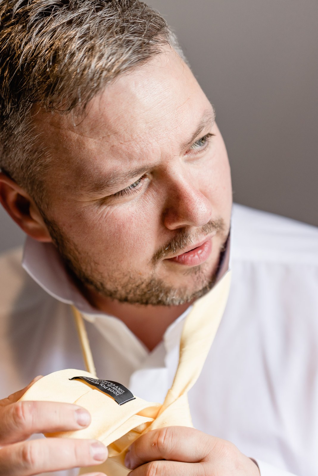 Close-up of the groom fastening his yellow tie