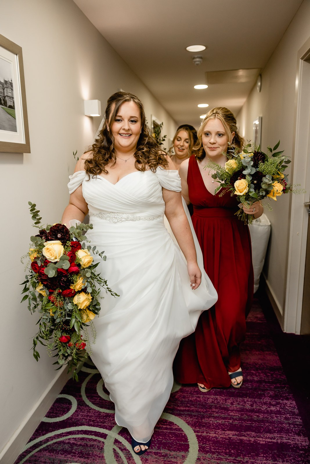 The bride and bridesmaids walk the hotel corridor carrying their bouquets