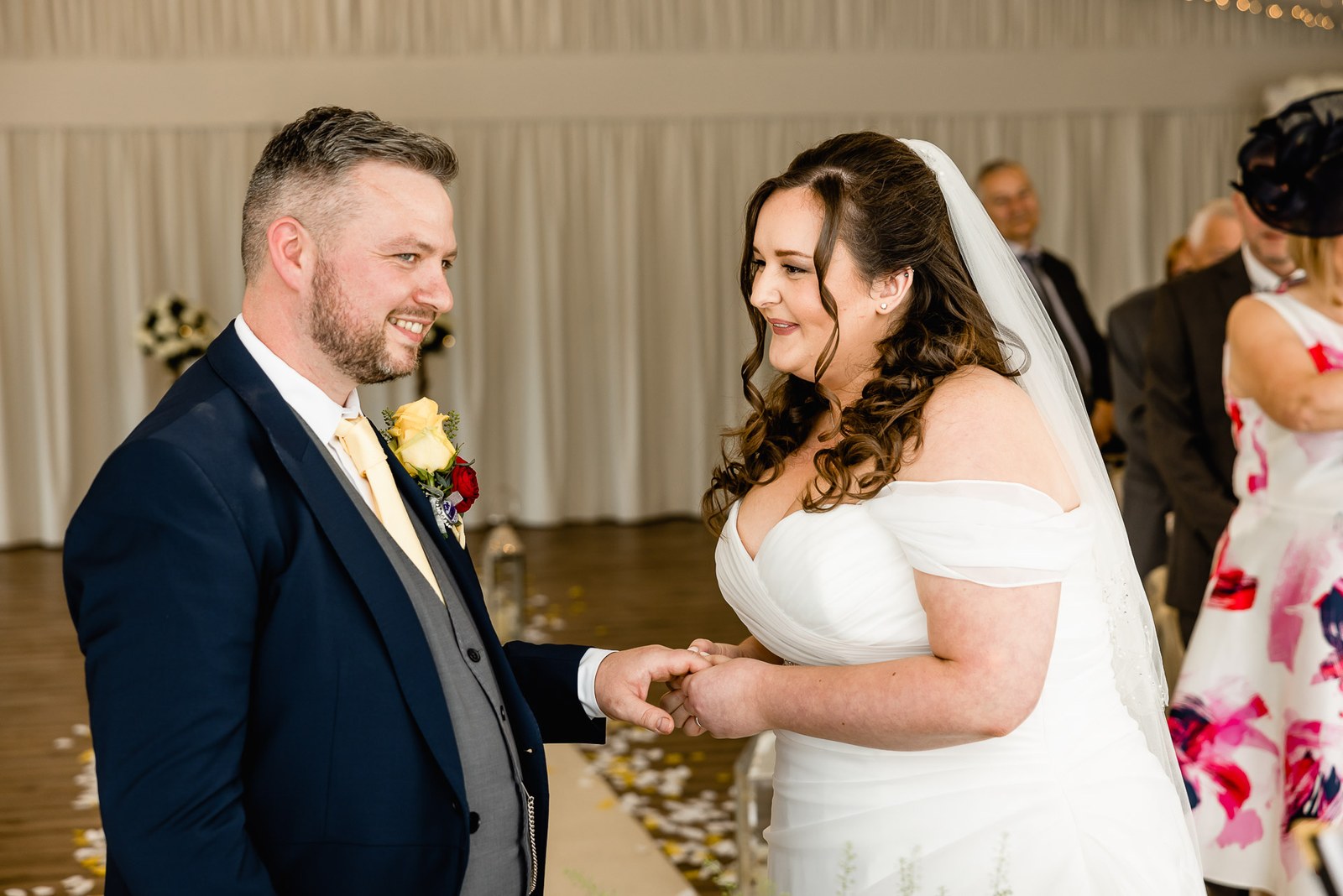 Bride and groom hold hands and smile during the ceremony