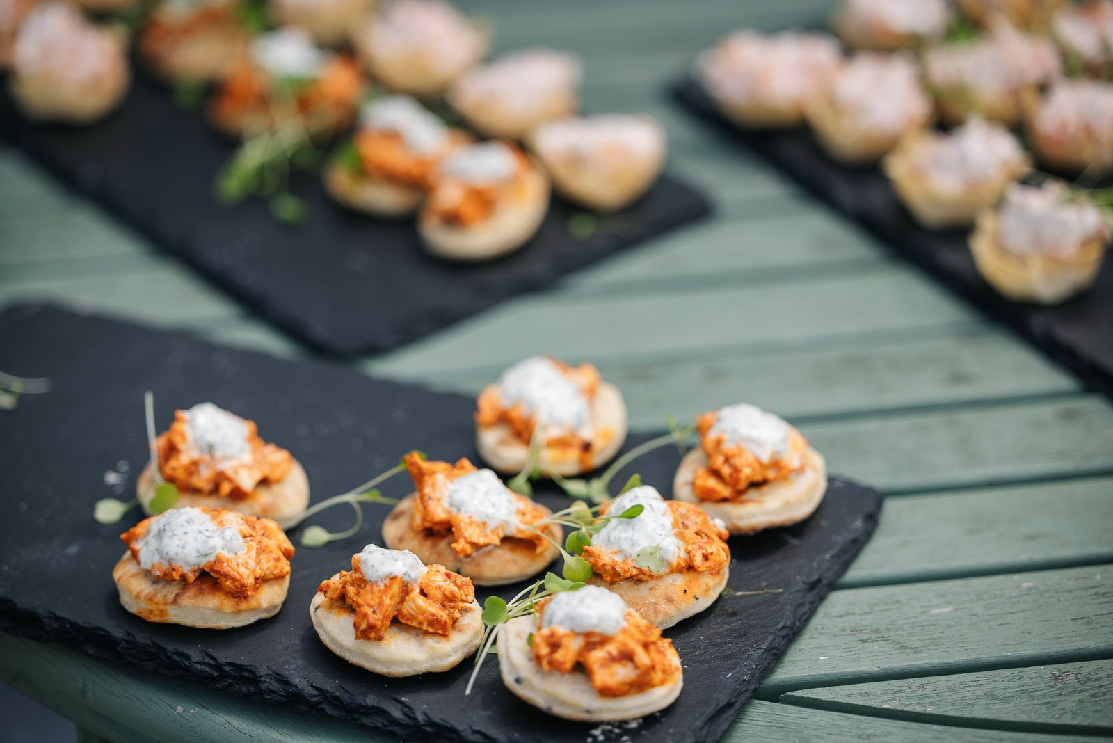 Canapes topped with pulled meat and cream arranged on slate boards