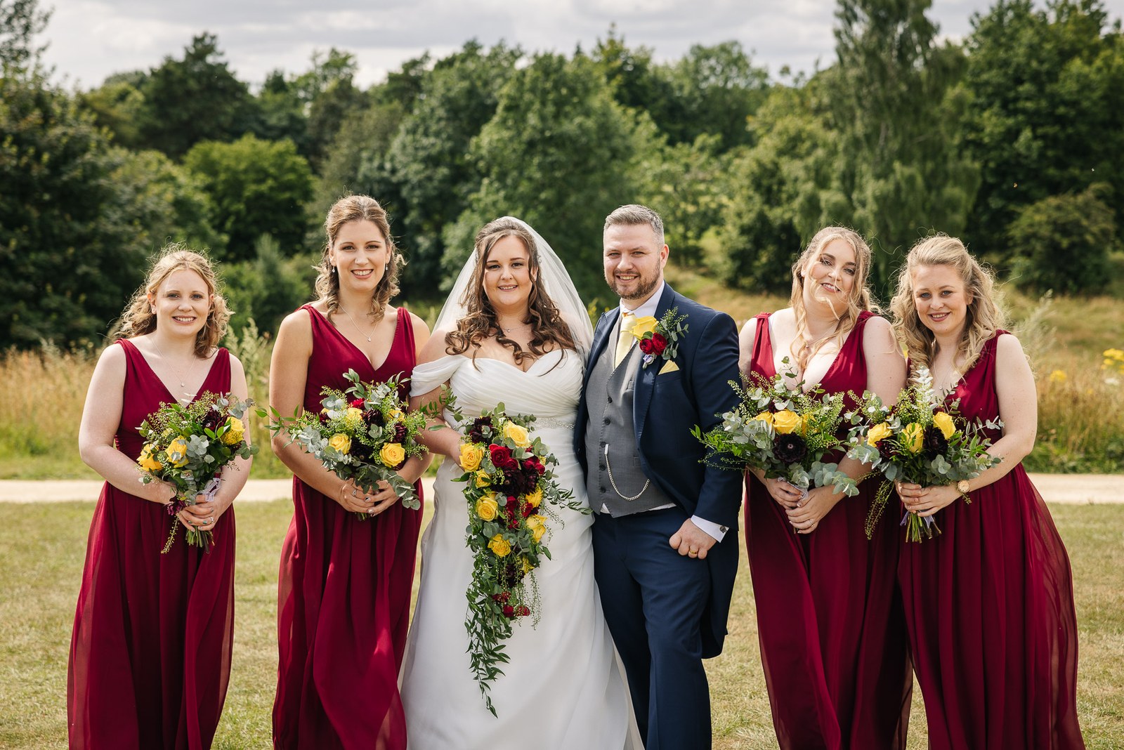 The couple with their bridesmaids in red on the green fairways