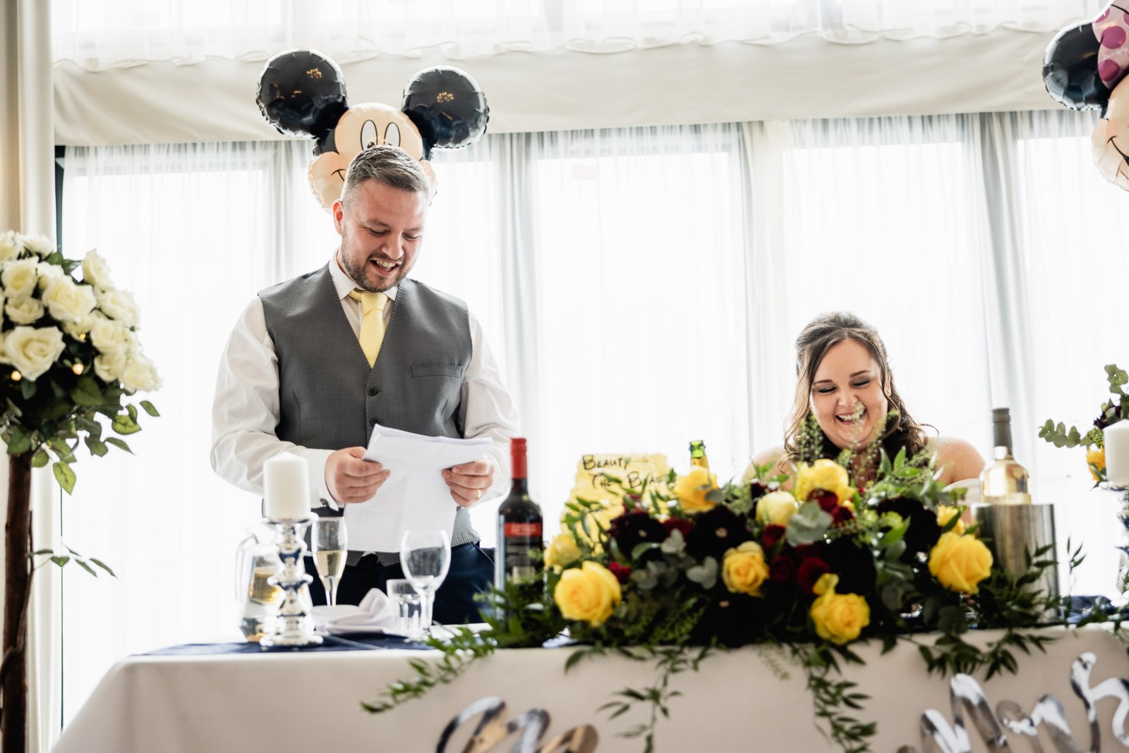 The groom reads his speech at the top table beneath balloon decorations