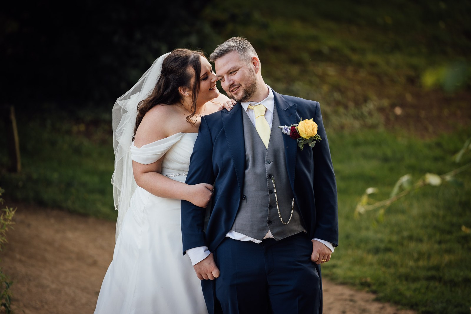 The bride whispers to the smiling groom on a garden path