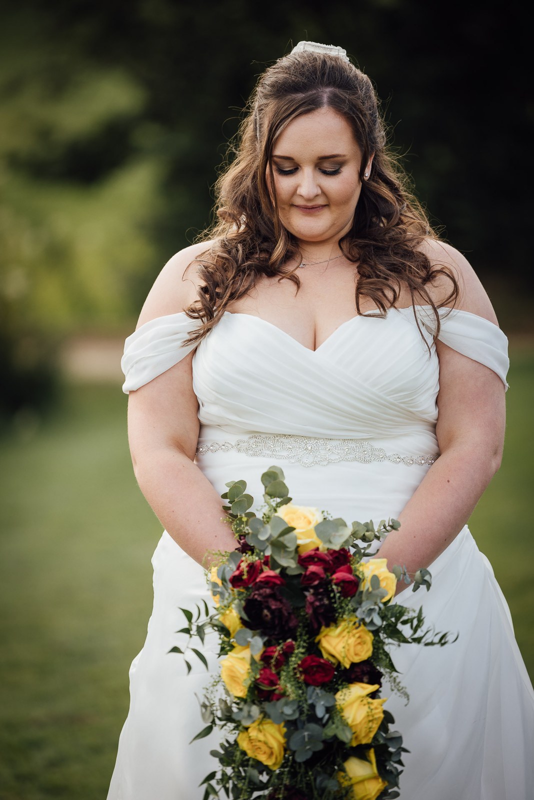 Portrait of the bride holding a trailing bouquet of red and yellow roses