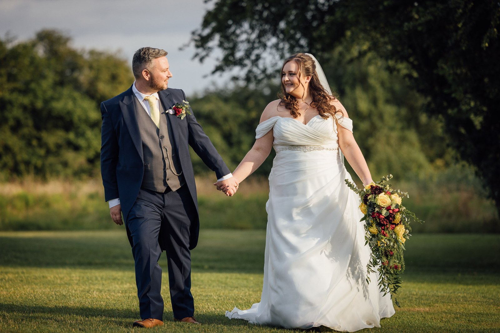 The couple walk hand in hand across the lawns at dusk