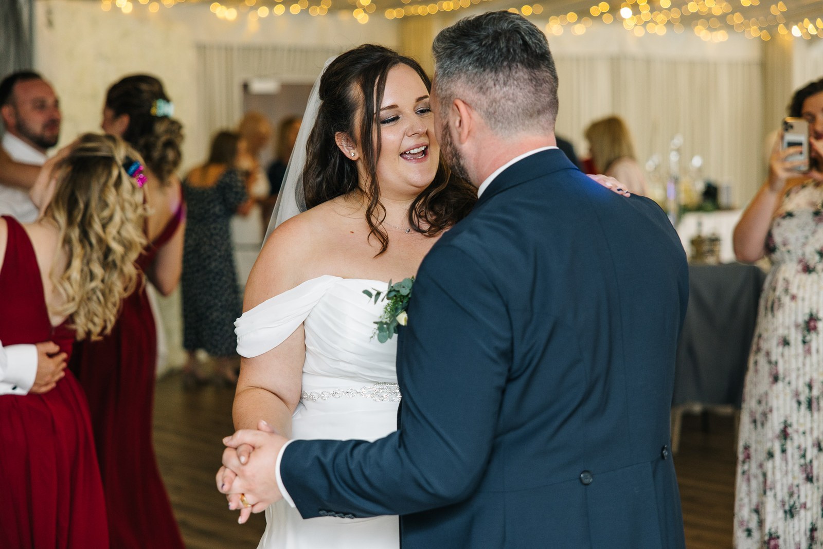The couple share their first dance beneath fairy lights as guests watch