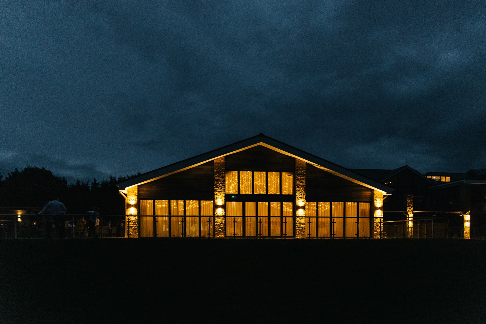 The clubhouse pavilion at Cotswolds Hotel & Spa glowing gold against the night sky