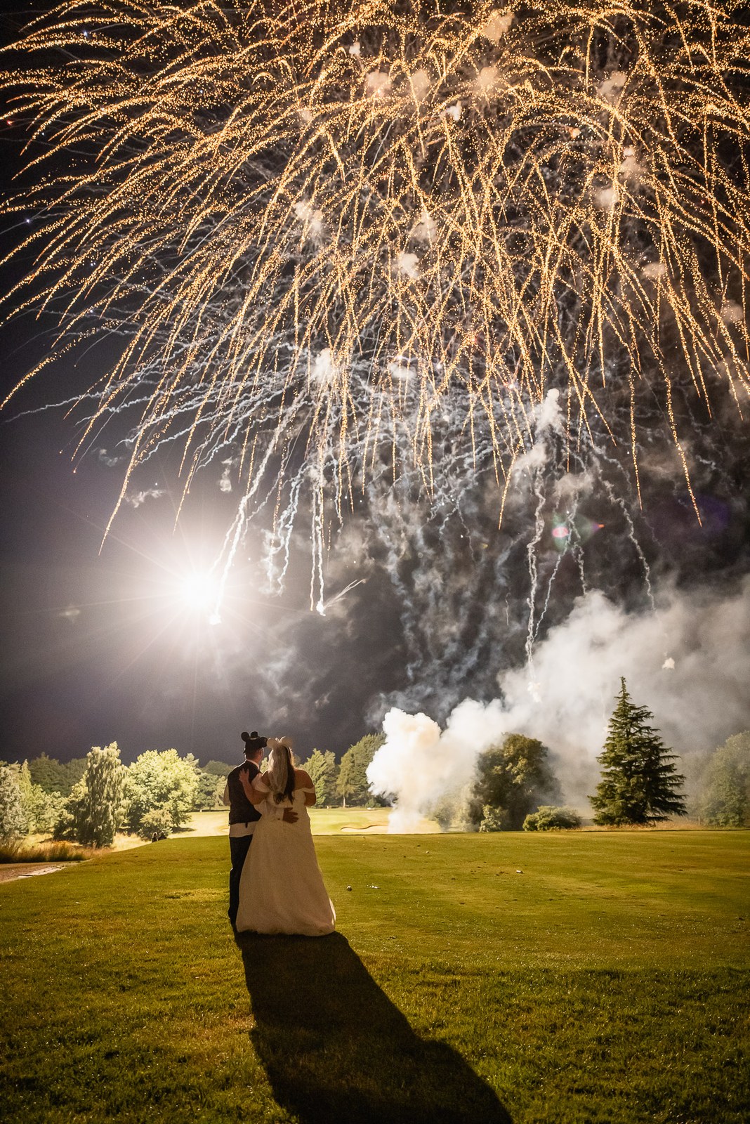 The couple silhouetted as fireworks burst over the golf course