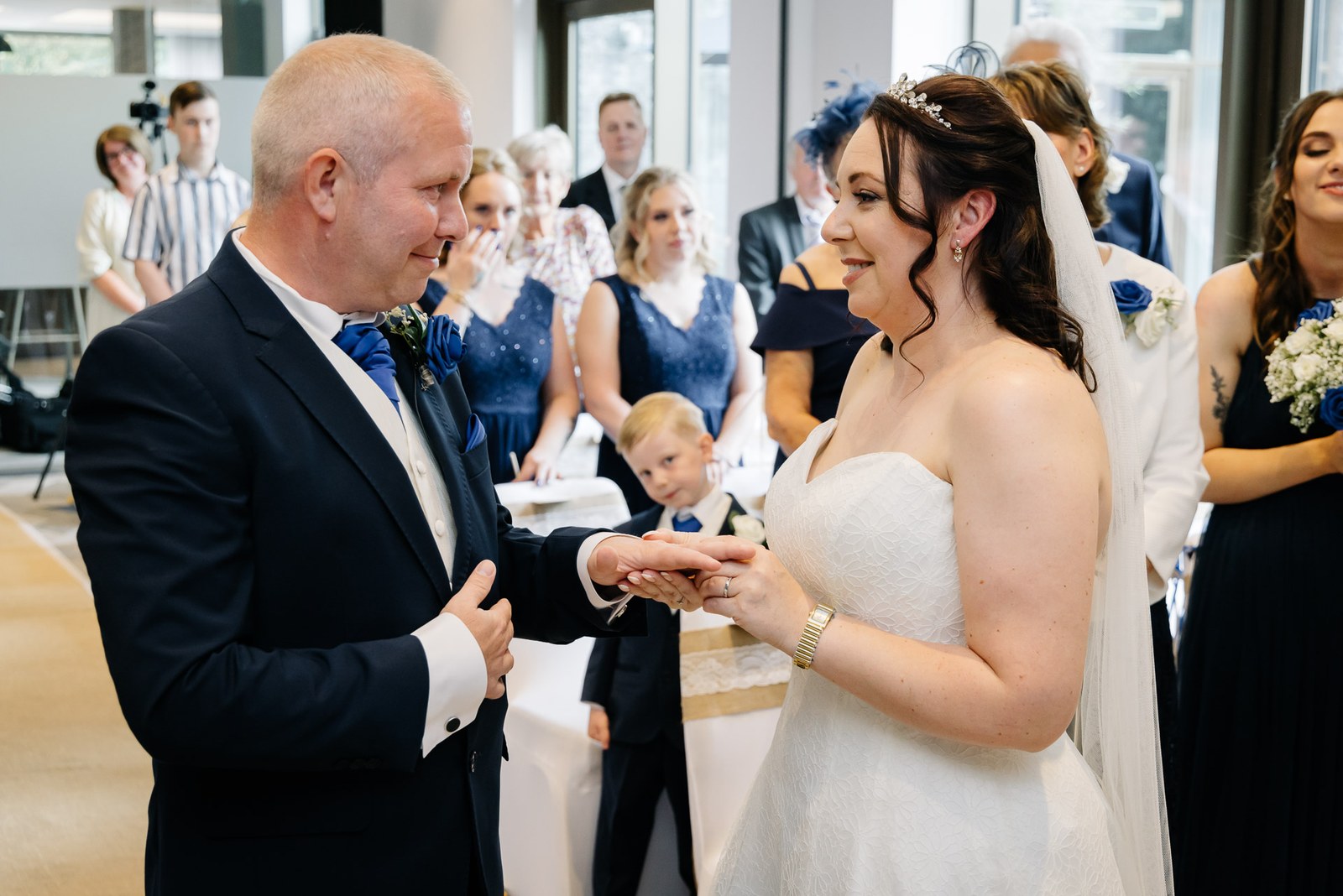 The couple exchanging rings during the ceremony, a young page boy standing between them