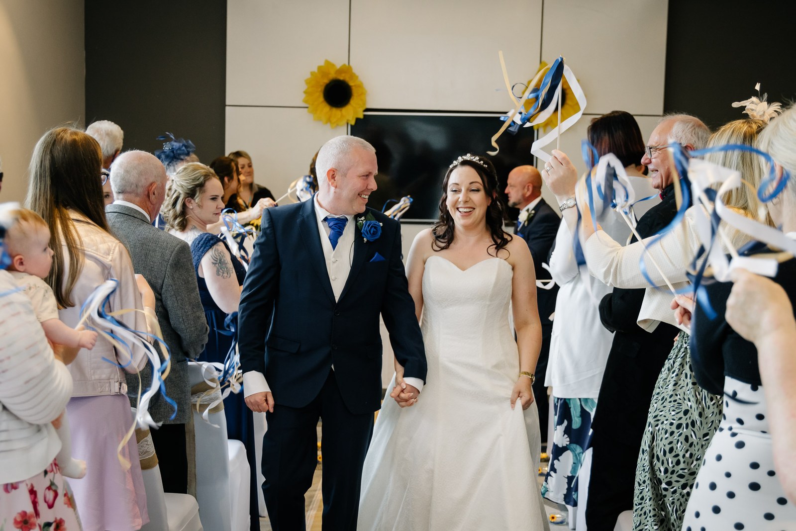 The couple walking back down the aisle through a guard of waving ribbon wands