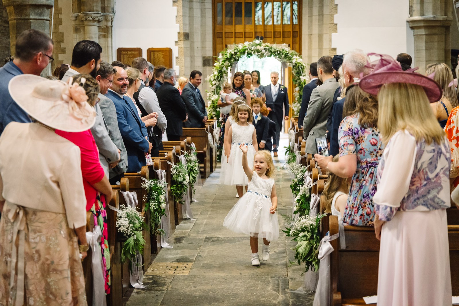 A flower girl walks the church aisle as guests look on