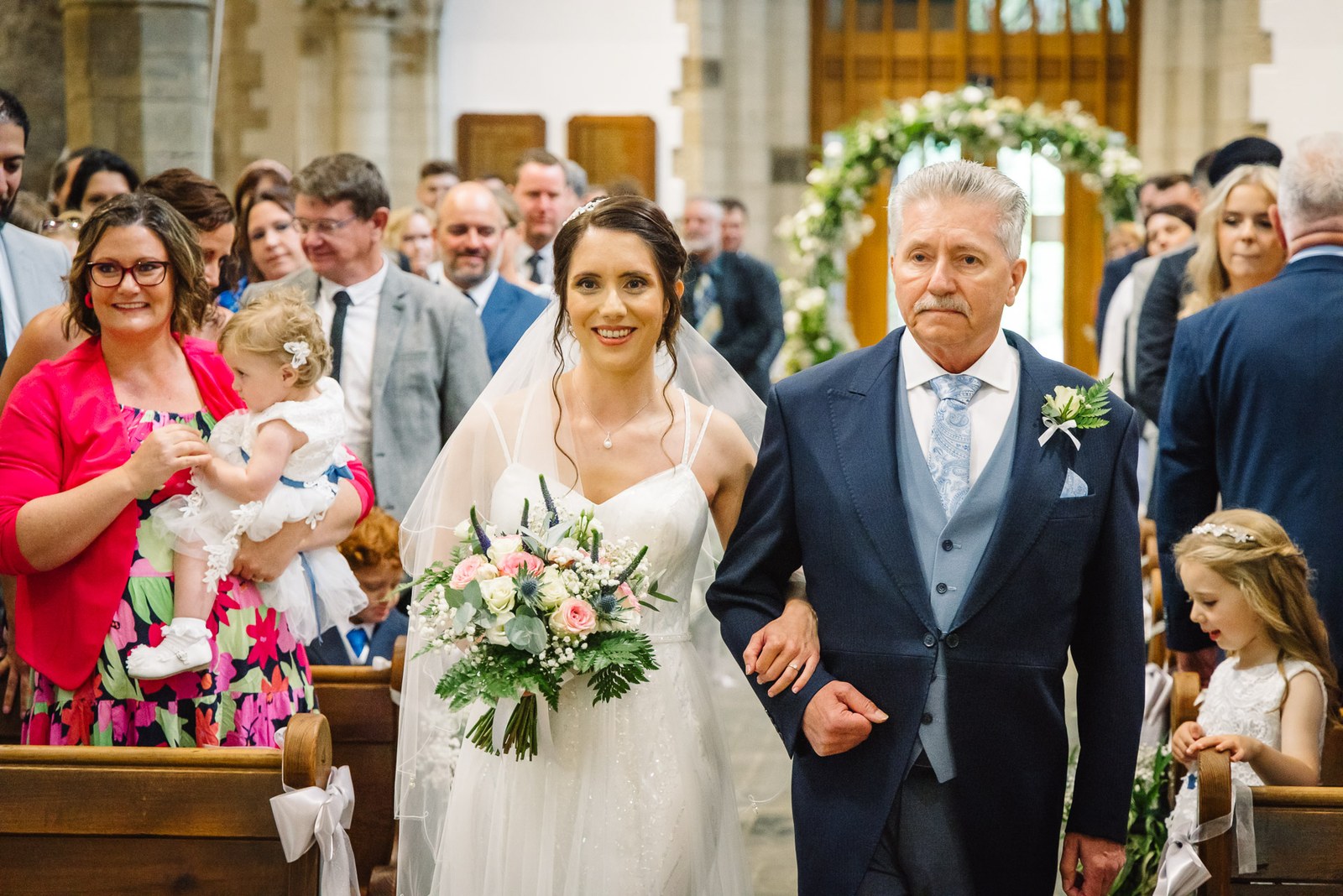 The bride walks down the church aisle on her father's arm