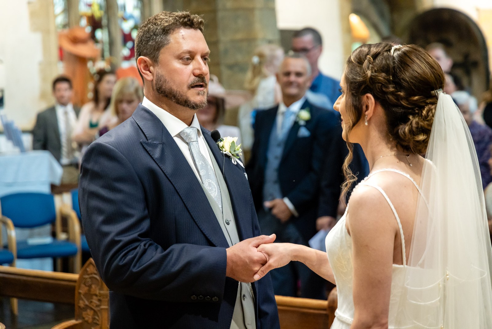 Bride and groom hold hands before the altar during the church ceremony