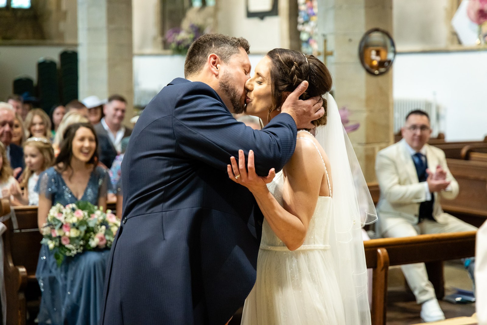 The newlyweds share their first kiss as guests applaud in the church