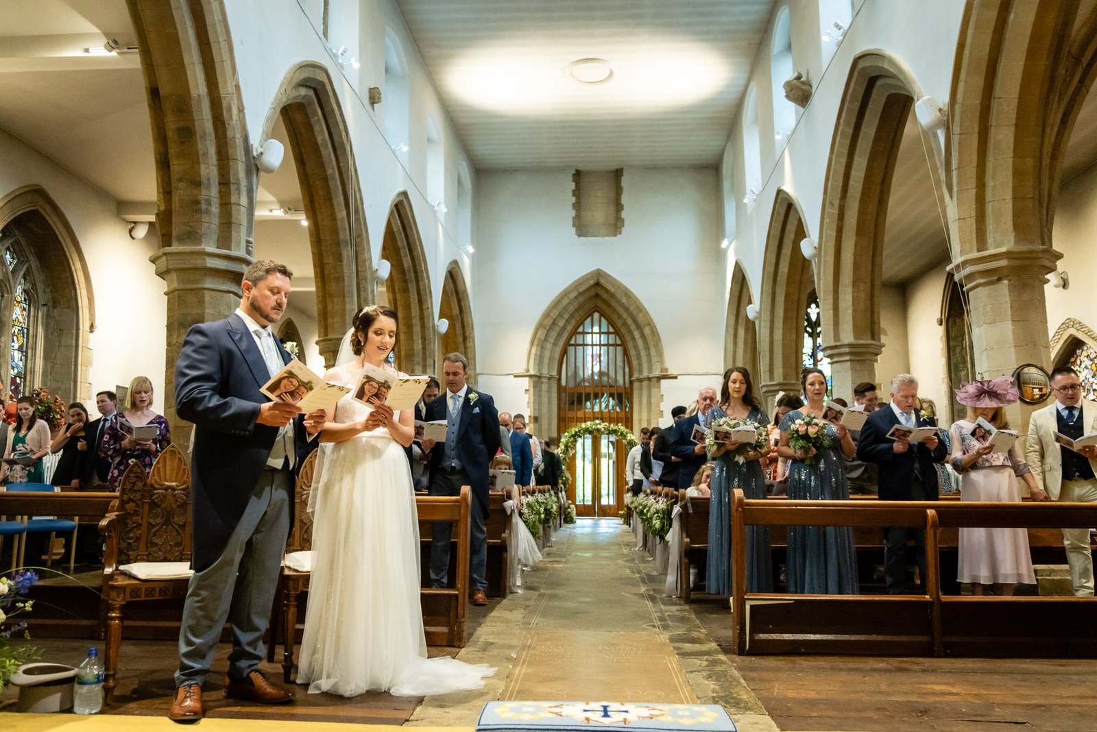 Wide view down the church nave, the couple at the front reading from their order of service