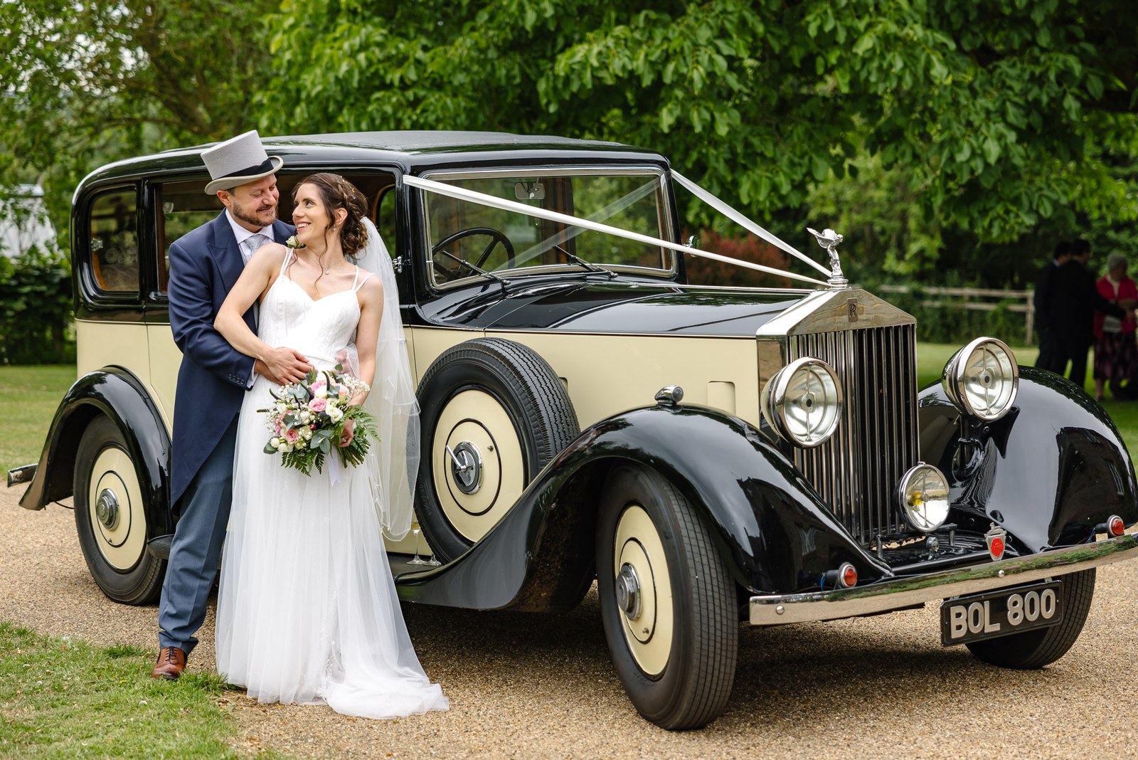 The couple pose by their ribboned vintage Rolls-Royce, the groom in a top hat
