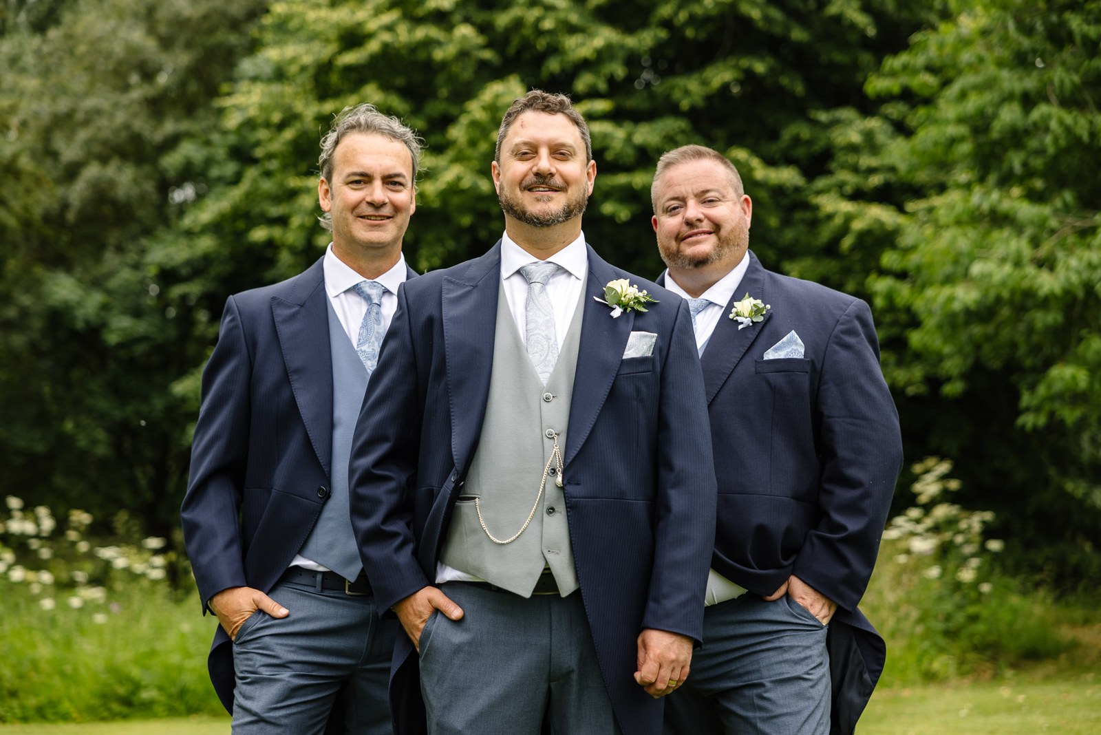 The groom and his groomsmen in navy suits among the greenery