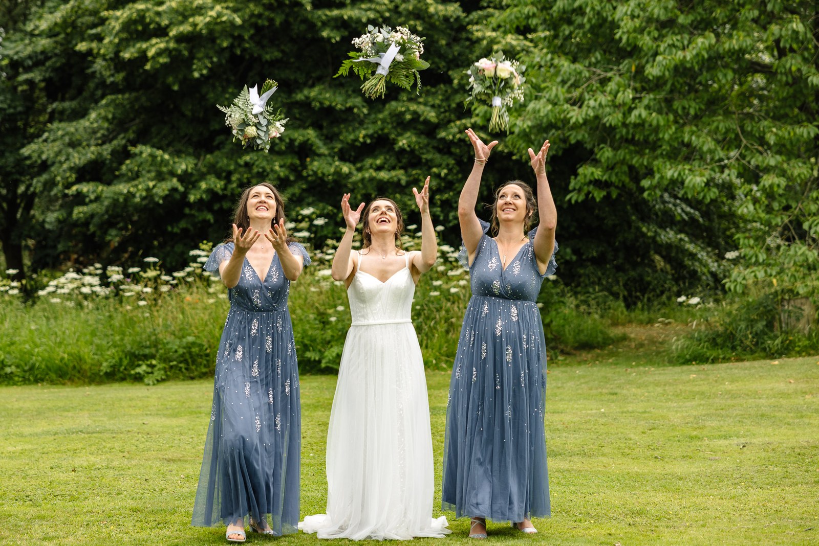 The bride and her bridesmaids toss their bouquets into the air