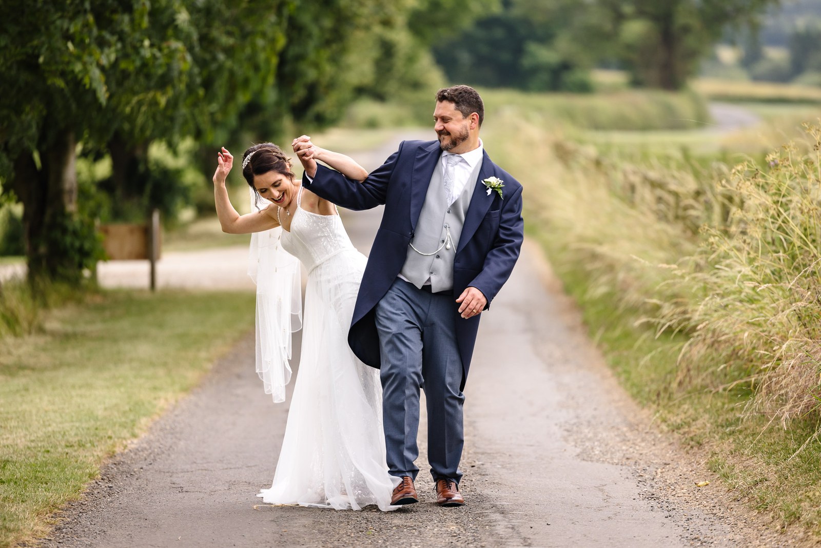 The couple stroll playfully down a country lane in the sunshine