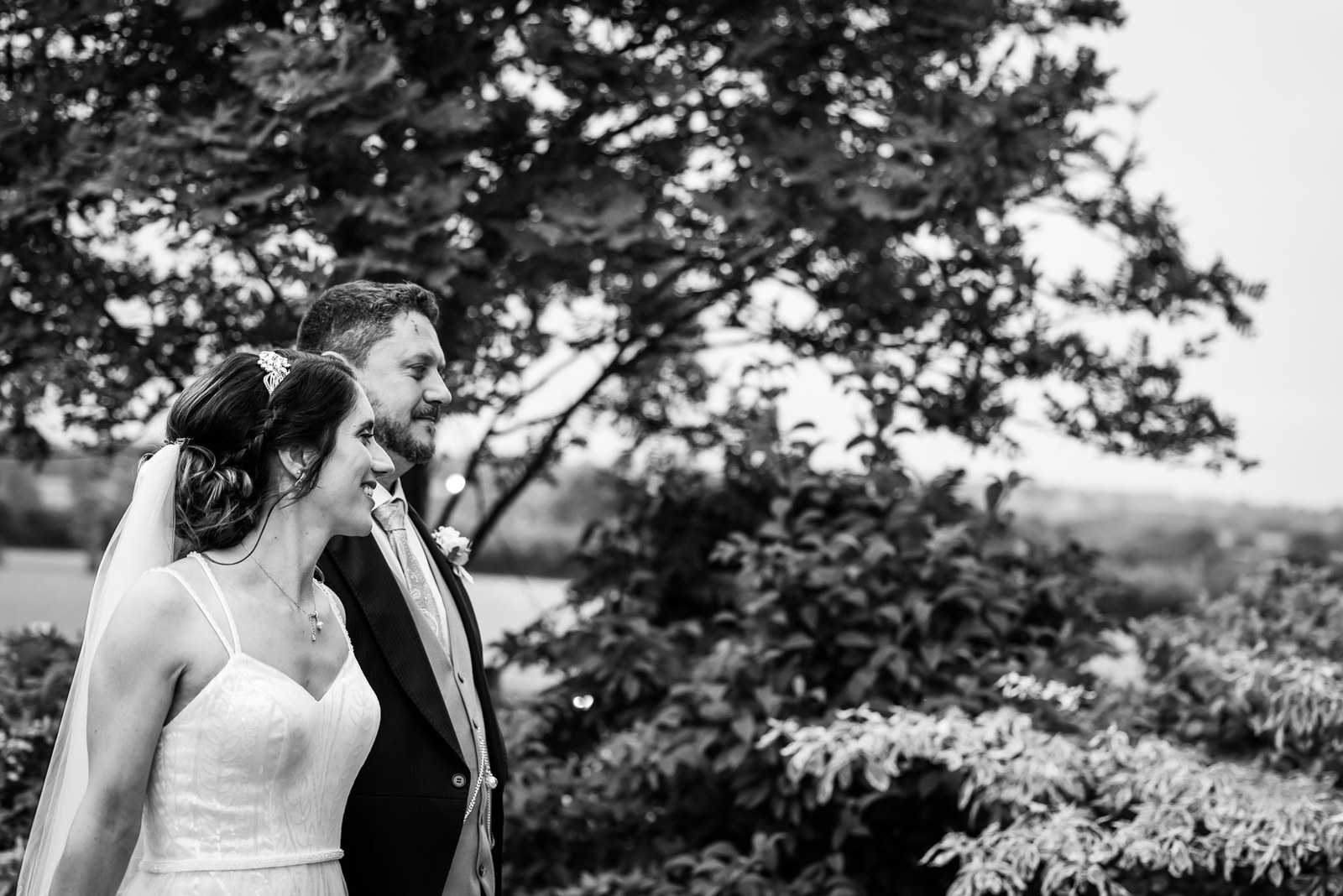 Black-and-white portrait of the couple laughing beneath a spreading tree