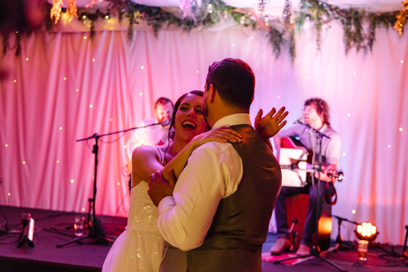 The newlyweds hold each other close during the first dance under pink lights