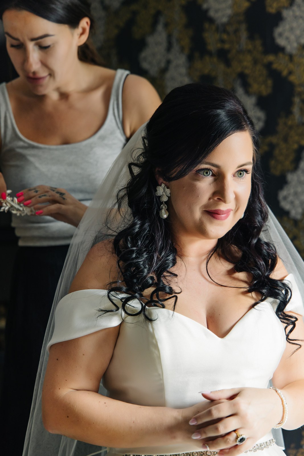A helper readies a jewelled hairpiece as the bride's veil is set
