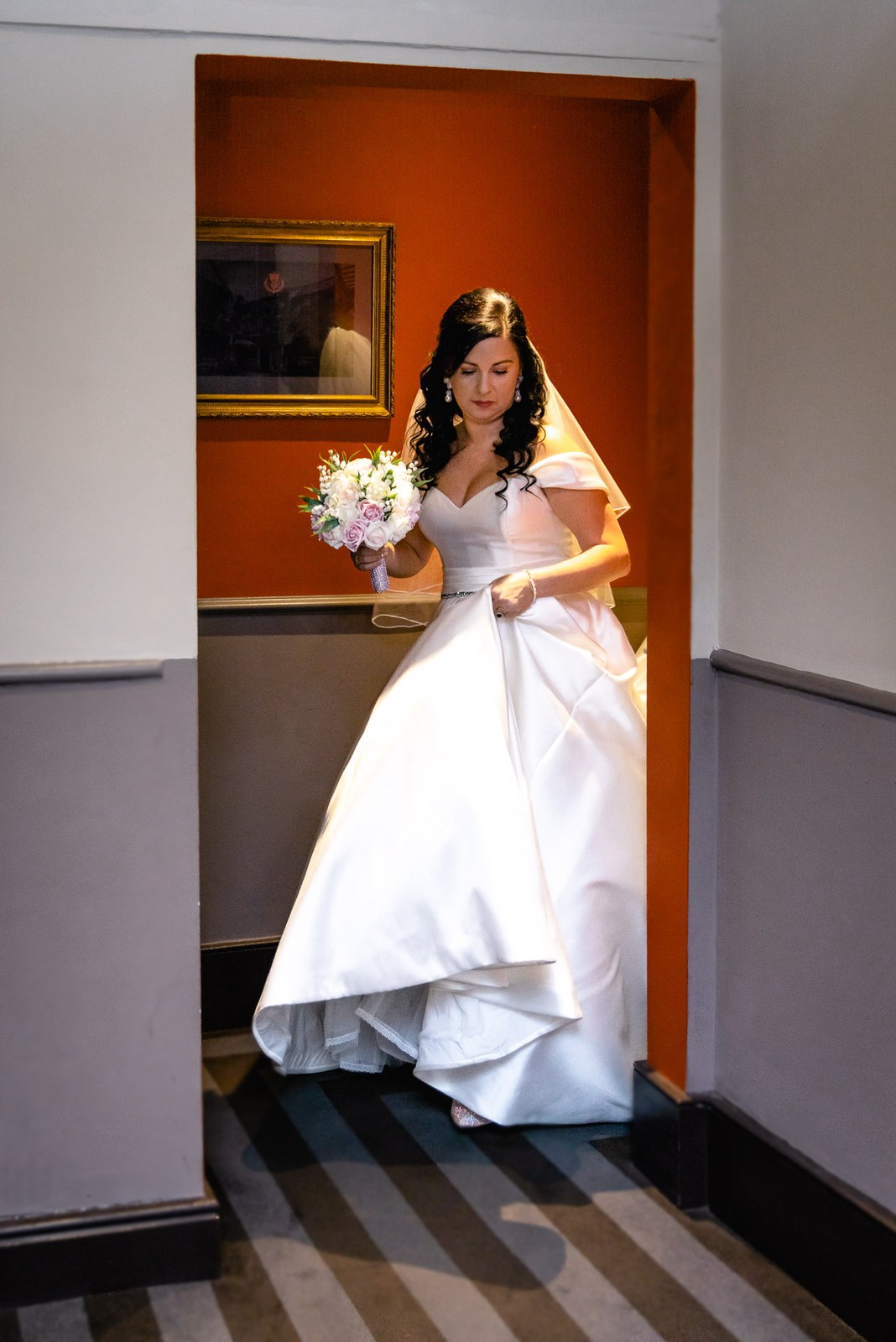 The bride waits in a doorway with her bouquet before the ceremony